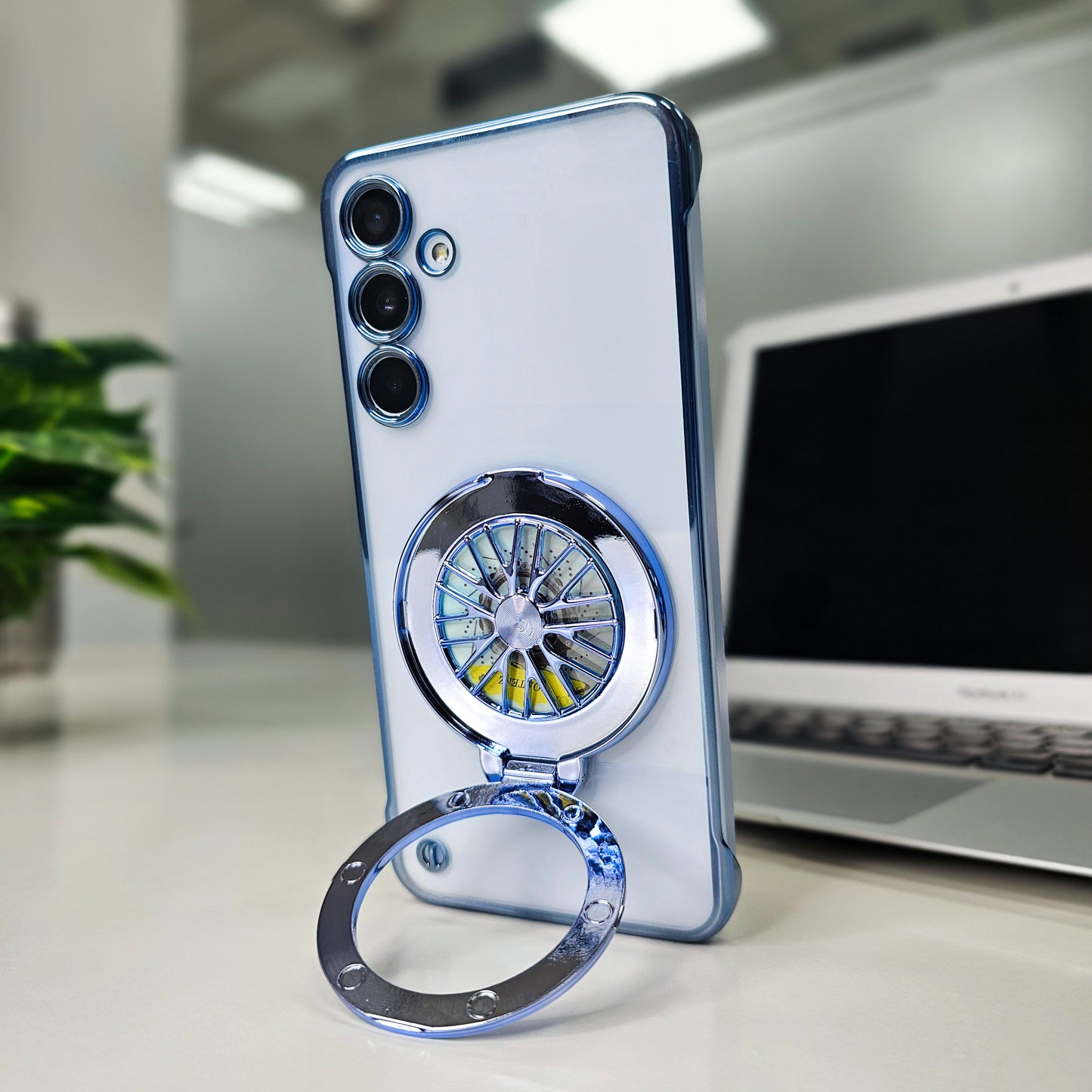 Phone case with wheel design ring holder on a desk with laptop and plant
