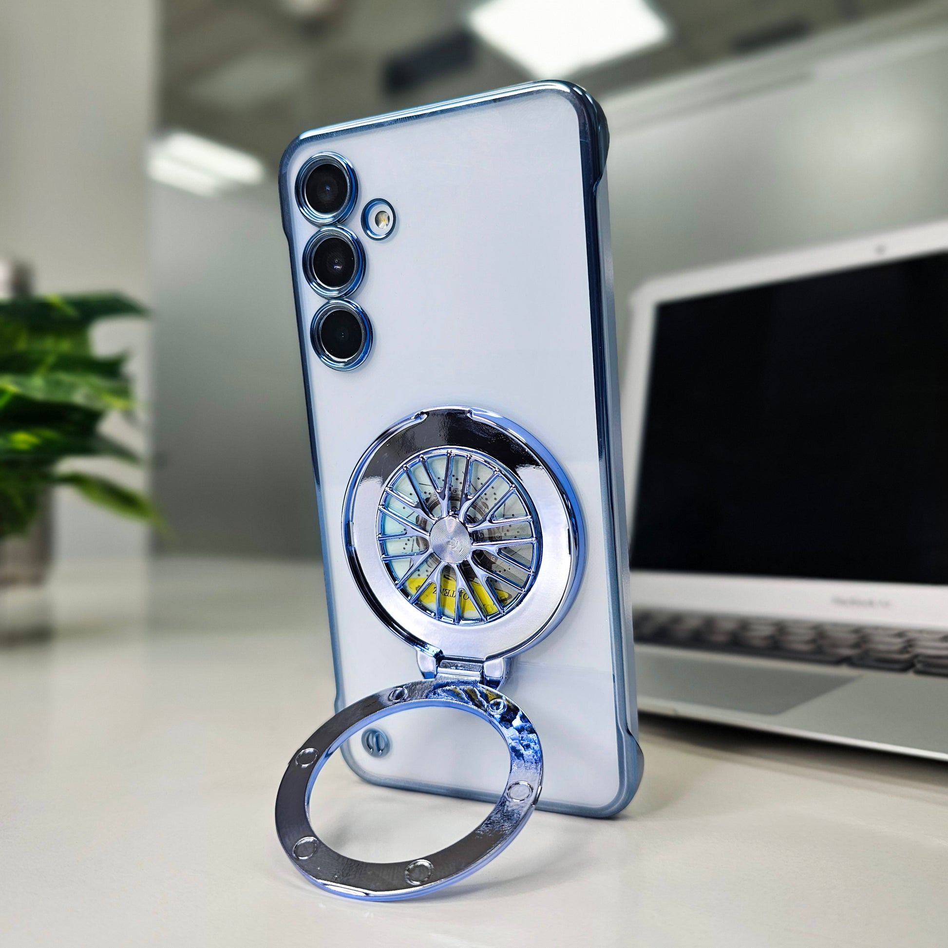 Phone case with wheel design ring holder on a desk with laptop and plant