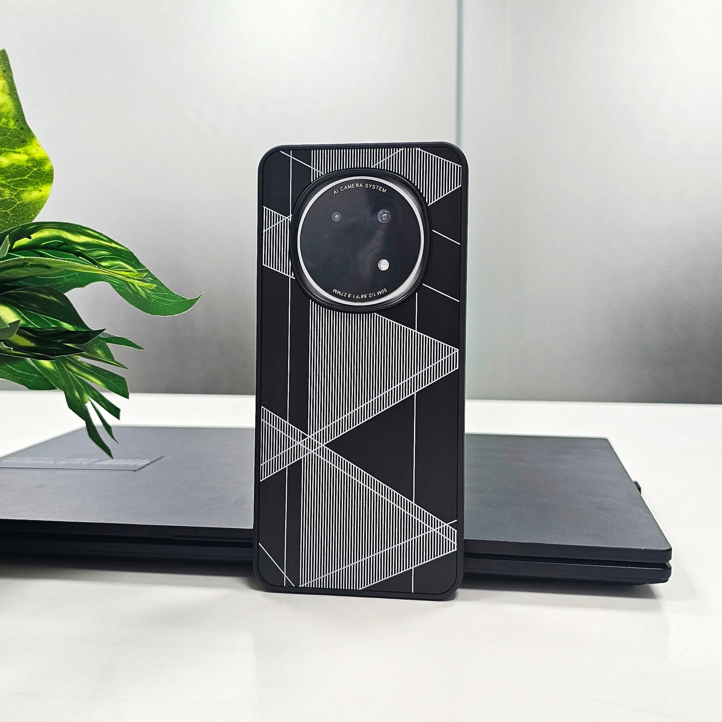 Phone case with geometric design on a white surface with a plant in the background