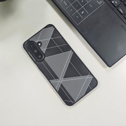 Phone case with geometric design on a light surface next to a laptop